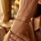 Gros plan sur un poignet de femme portant un bracelet jonc en or rouge 18 carats au design bambou, éclat solaire et chaleureux.
