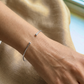 Poignet d'une femme portant un bracelet jonc ouvert en or blanc massif 18 carats, fil rond de 1,5 mm avec finitions boules.