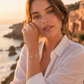 Bracelet jonc ouvert en or jaune 18 carats avec pierres de couleur porté par une femme de profil au crépuscule.