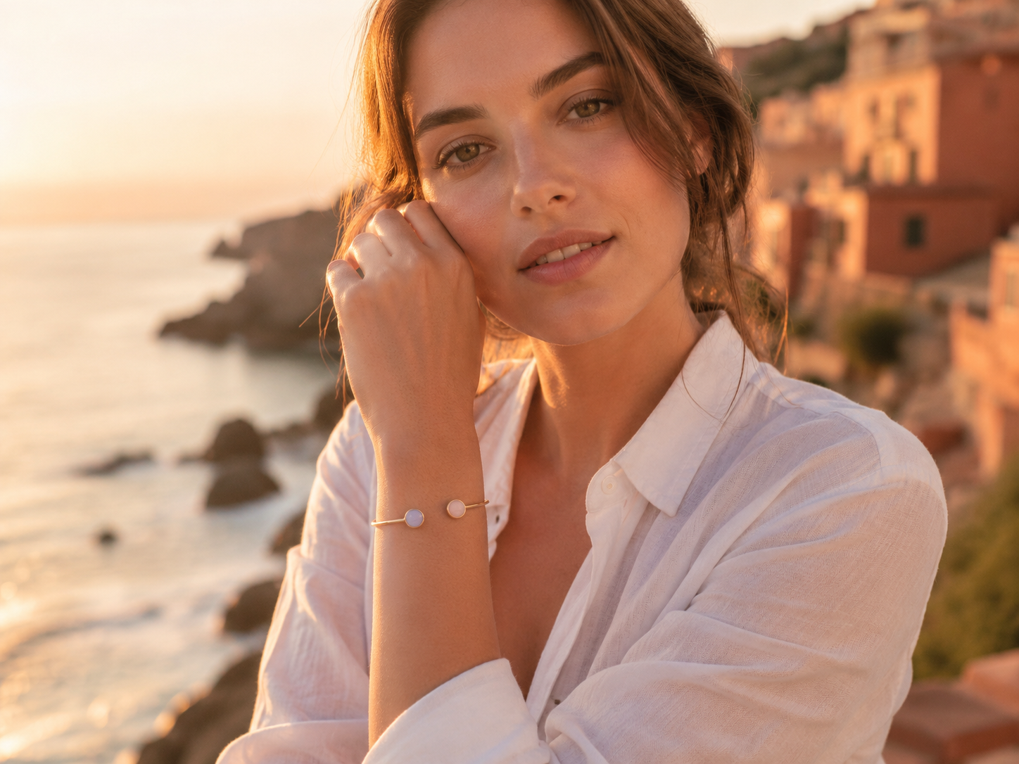 Bracelet jonc ouvert en or jaune 18 carats avec pierres de couleur porté par une femme de profil au crépuscule.