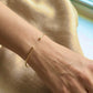 Gros plan sur le poignet d'une femme portant un bracelet jonc ouvert en or jaune massif 18 carats, fil rond de 1,5 mm avec finitions boules.