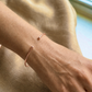 Poignet d'une femme portant un bracelet jonc ouvert en or rose massif 18 carats, fil rond de 1,5 mm avec finitions boules.