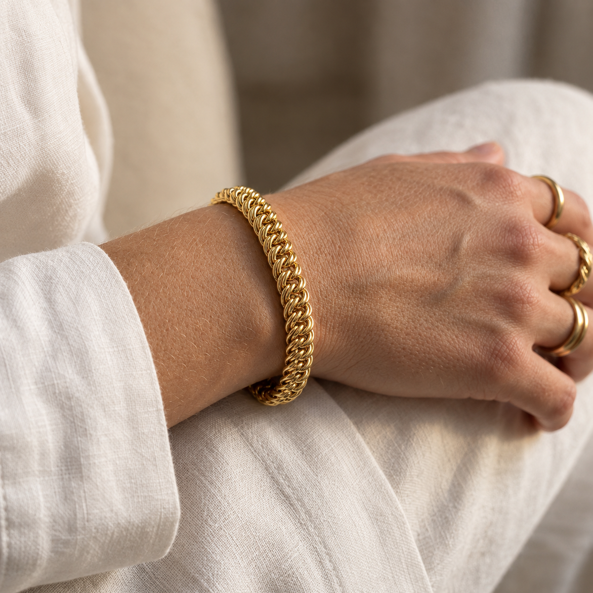 Gros bracelet or femme maille américaine plate en or jaune 18 carats porté au poignet au soleil.
