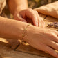 Gros plan sur le poignet d'une femme portant un bracelet en maille grain de café alterné en or jaune 18 carats, un bijou de caractère au style solaire.