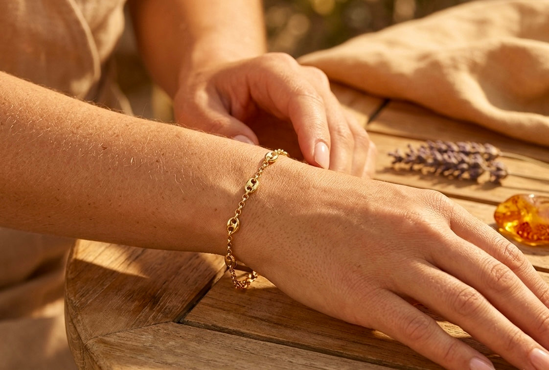 Gros plan sur le poignet d'une femme portant un bracelet en maille grain de café alterné en or jaune 18 carats, un bijou de caractère au style solaire.
