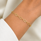 Bracelet chaîne maille marine plate en or jaune 18 carats porté au poignet d'une femme.