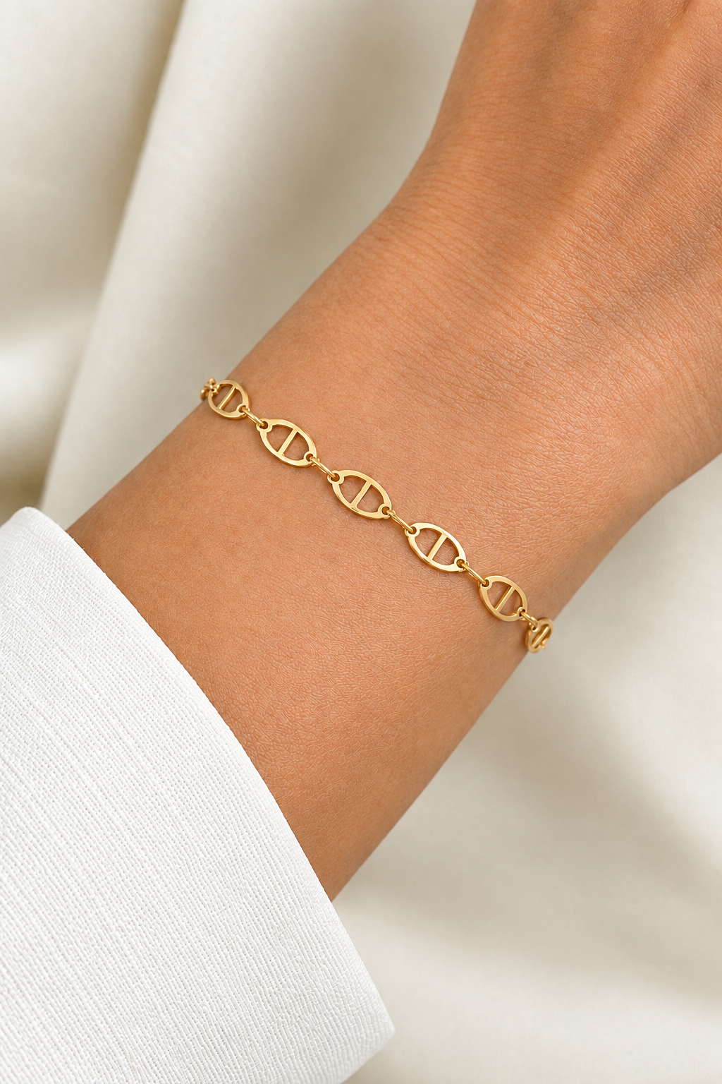 Bracelet chaîne maille marine plate en or jaune 18 carats porté au poignet d'une femme.