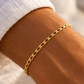 Bracelet en or massif 18 carats maille cheval porté au poignet d'un homme au coucher du soleil.