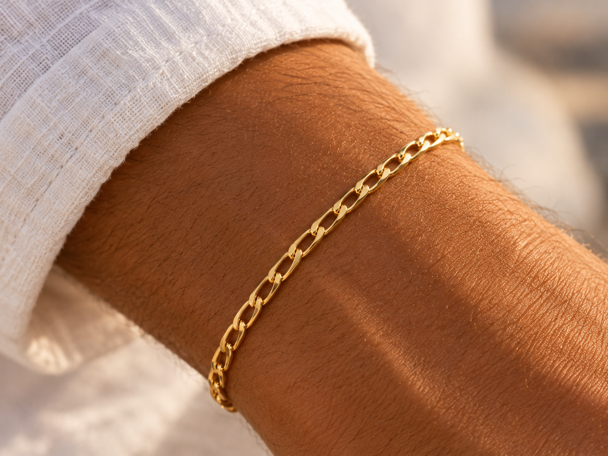Bracelet en or massif 18 carats maille cheval porté au poignet d'un homme au coucher du soleil.