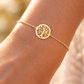 Bracelet symbole Arbre de Vie en or jaune 18 carats porté avec délicatesse au poignet d'une femme au coucher du soleil.