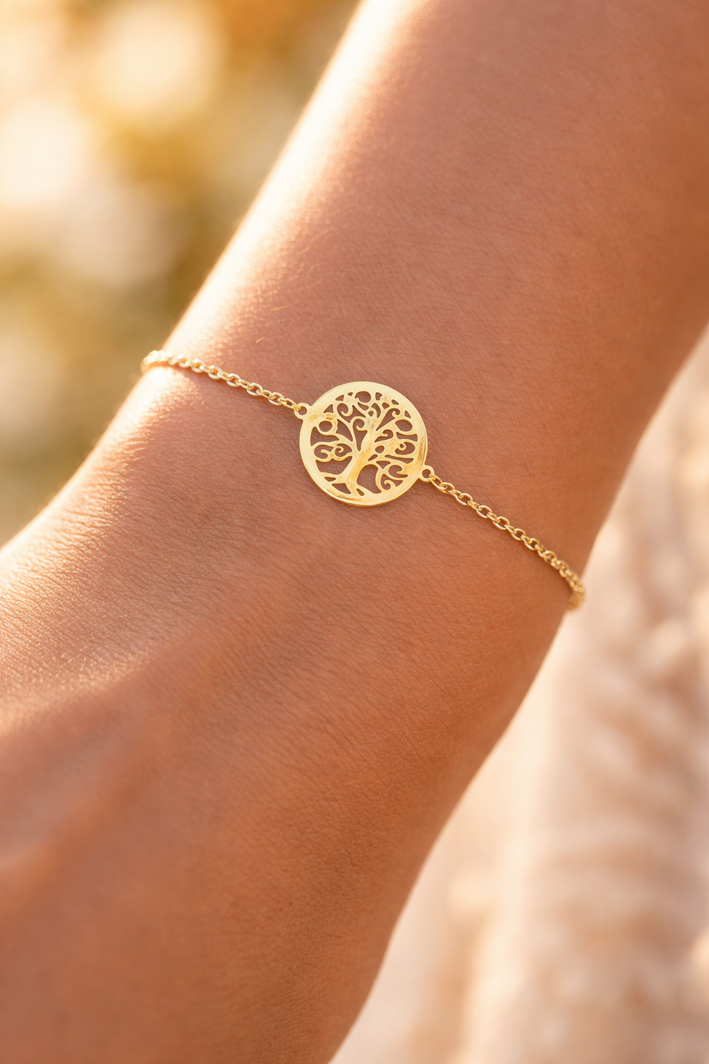 Bracelet symbole Arbre de Vie en or jaune 18 carats porté avec délicatesse au poignet d'une femme au coucher du soleil.