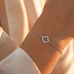 Bracelet en or blanc 18 carats orné d'un trèfle à quatre feuilles serti de diamants porté au poignet d'une femme 