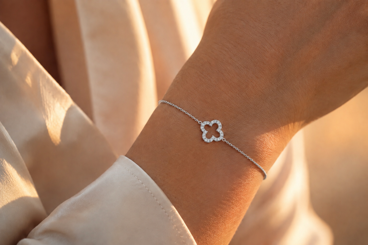 Bracelet en or blanc 18 carats orné d'un trèfle à quatre feuilles serti de diamants porté au poignet d'une femme 