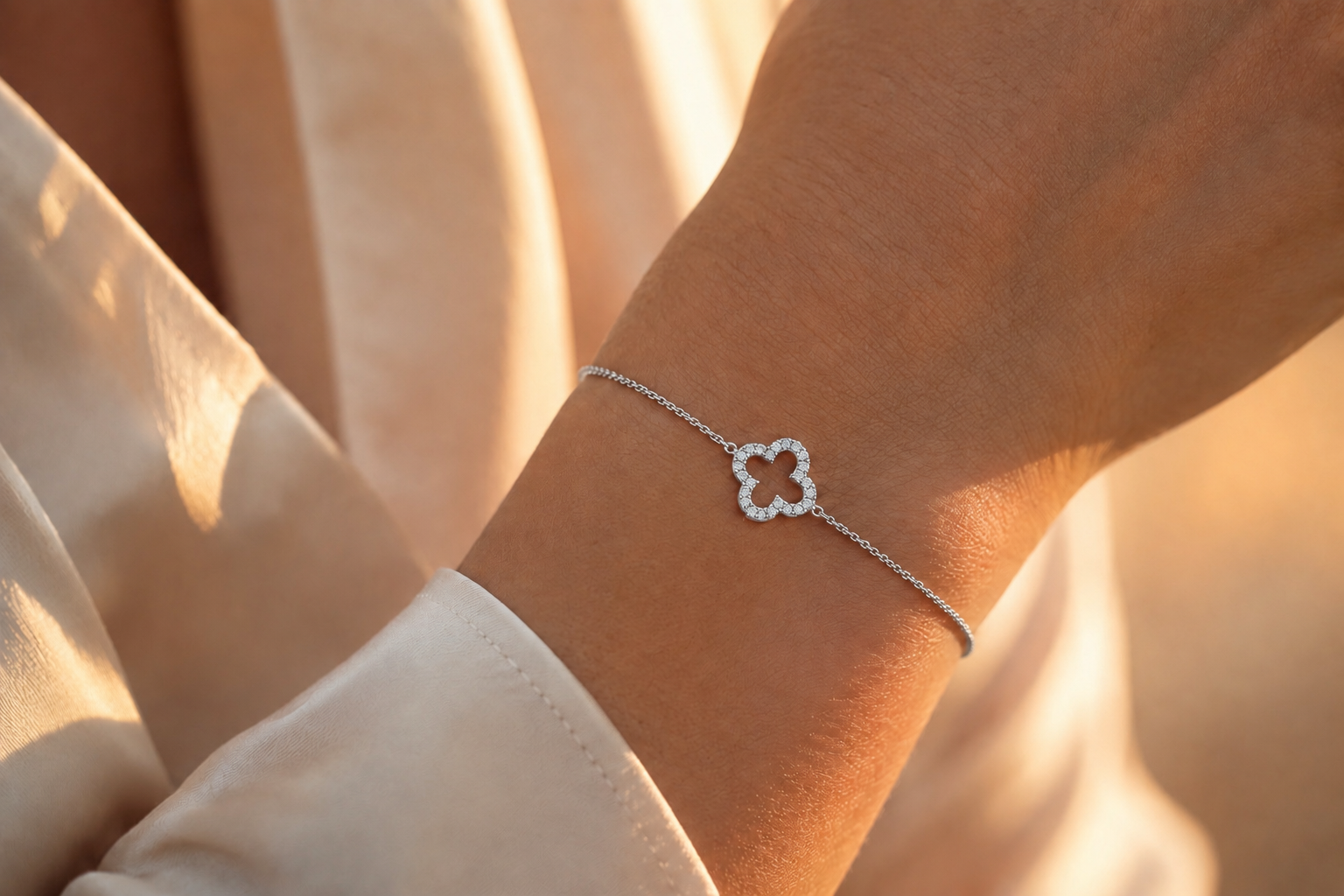 Bracelet en or blanc 18 carats orné d'un trèfle à quatre feuilles serti de diamants porté au poignet d'une femme 