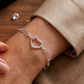 Bracelet trombone en or blanc 18 carats avec fermoir en forme de coeur porté au poignet d'une femme