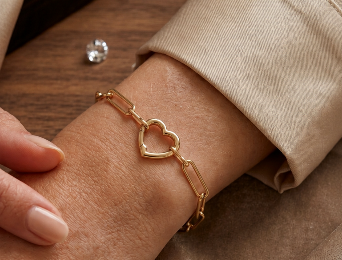 Bracelet trombone en or jaune 18 carats avec fermoir en forme de coeur porté au poignet d'une femme.