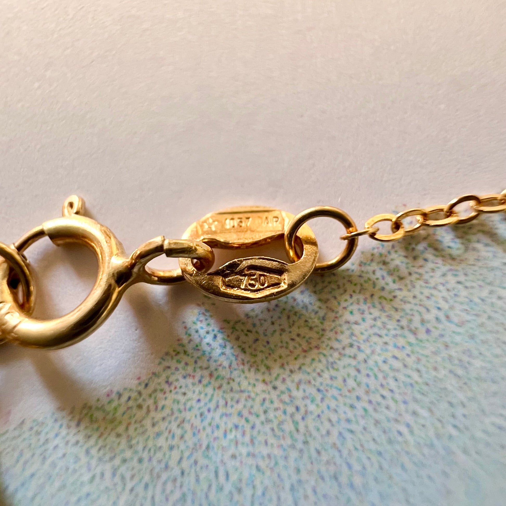 Gros plan du poinçon de garantie officiel 750 de l'or 18 carats sur l'attache du fermoir de la chaîne de main en or.