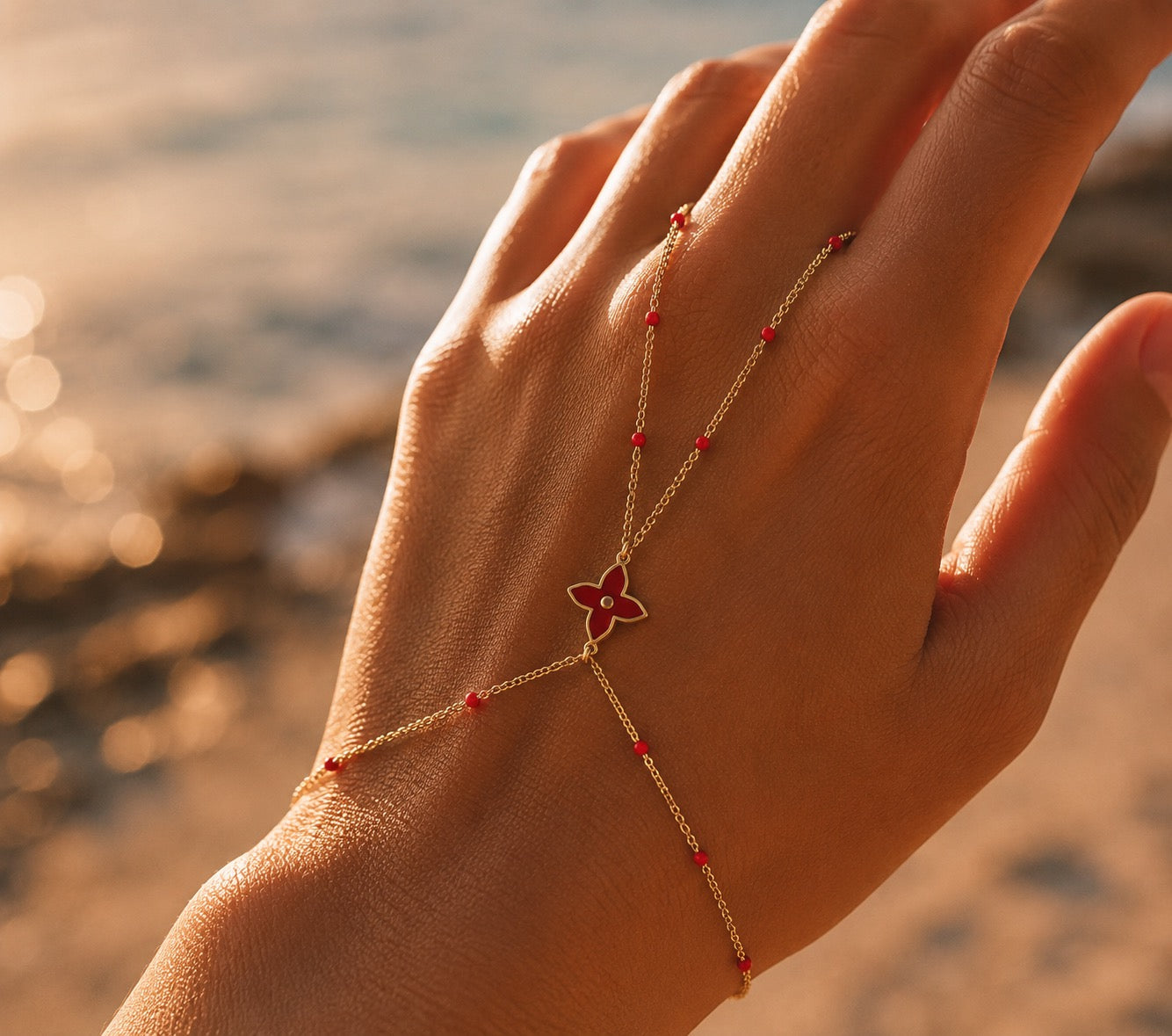 Rendu porté d'un passe-main en or jaune 18 carats avec motif floral et touches de résine rouge passion.