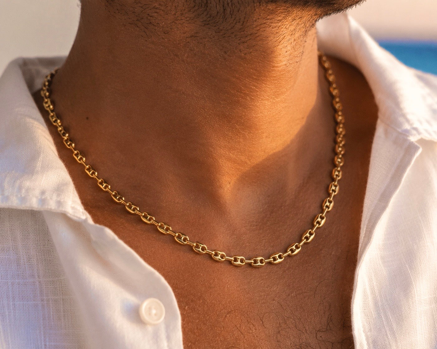 Gros plan sur un homme portant une chaîne en or jaune 18 carats maille grain de café, un collier de luxe au style méditerranéen.