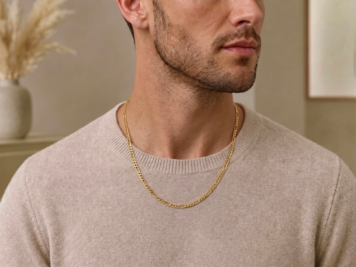 Chaîne homme maille Figaro en or jaune 18 carats portée sur le torse d'un homme.