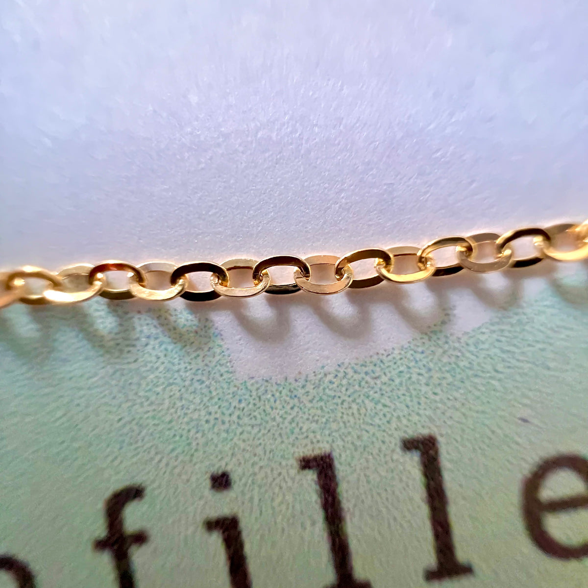 Détail macro des maillons plats polis miroir d'une chaîne maille forçat pour homme en or jaune 18 carats.