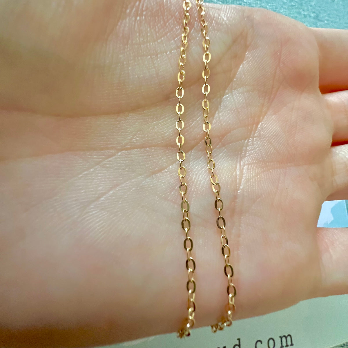 Chaîne en or jaune 18 carats maille forçat miroir drapée sur une main ouverte pour en apprécier la finesse et la brillance.