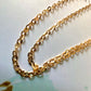 Chaîne en or jaune 18 carats maille forçat miroir captant la lumière naturelle du soleil.