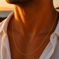 Gros plan sur un homme portant une chaîne maille forçat miroir en or jaune 18 carats de 60 cm, un collier masculin élégant et brillant.