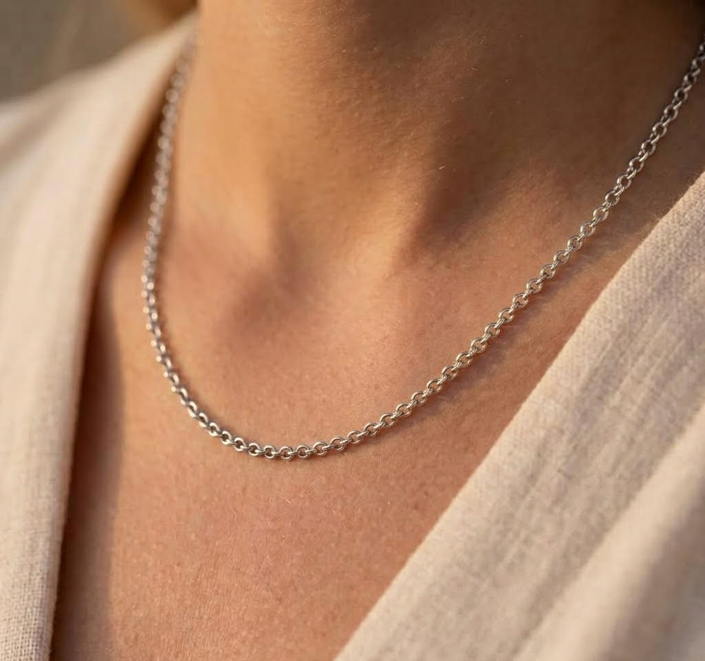 Chaîne de cou maille forçat ronde massive en or blanc 18 carats portée au cou par une femme