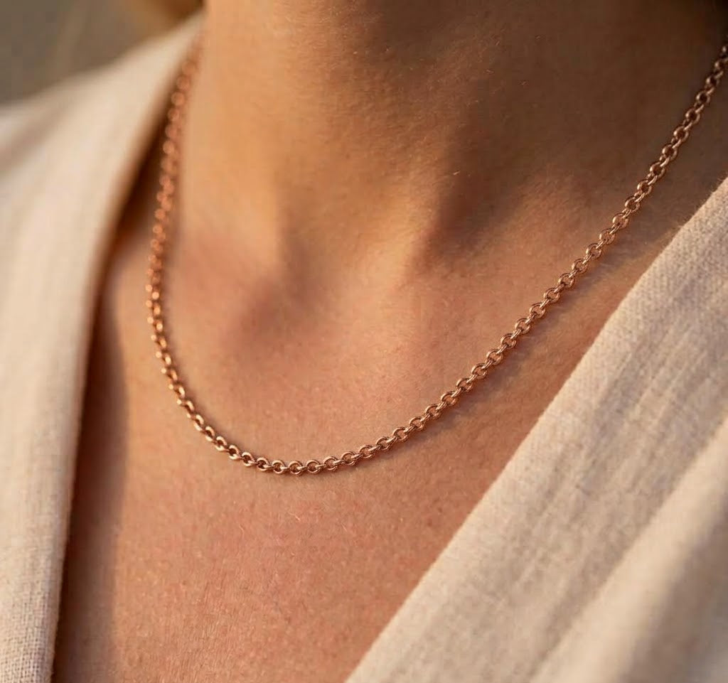 Chaîne de cou maille forçat ronde massive en or rouge (rose) 18 carats portée au cou par une femme
