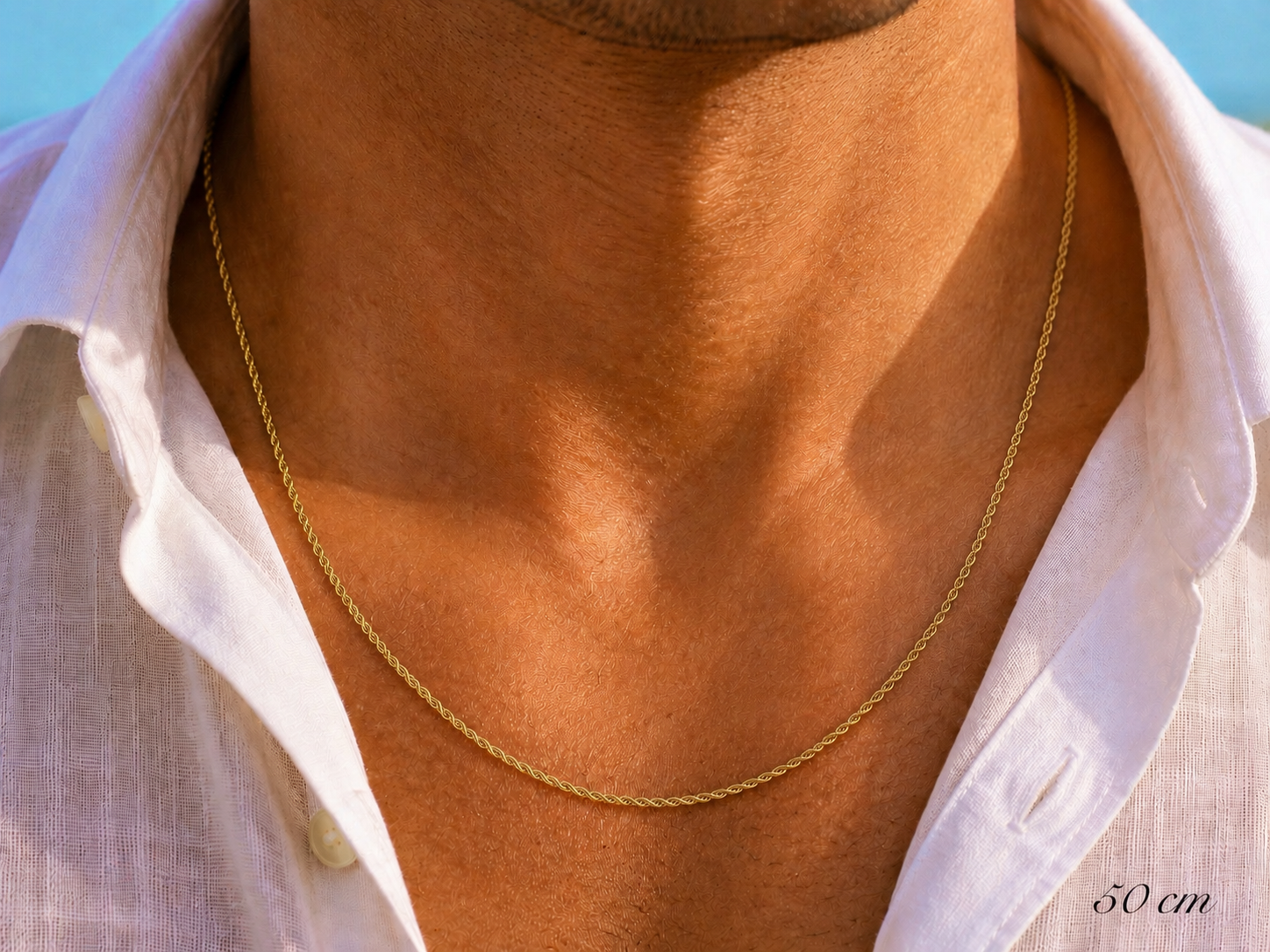 Gros plan sur un homme portant une chaîne en or jaune 18 carats maille corde, longueur 50 cm sur une chemise en lin.
