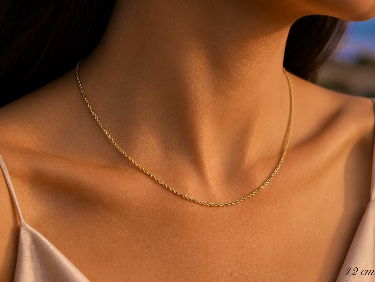Gros plan sur le cou d'une femme portant une chaîne torsadée en or jaune 18 carats maille corde, longueur 42 cm.