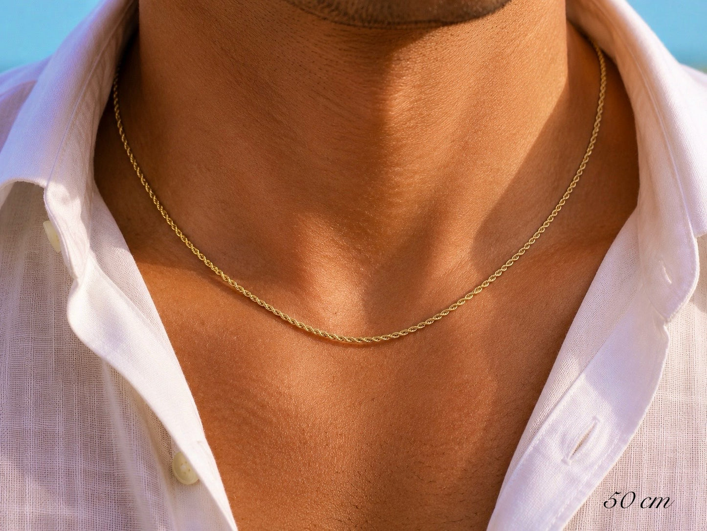 Gros plan sur un homme portant une chaîne en or jaune 18 carats maille corde, longueur 50 cm sur une chemise en lin.
