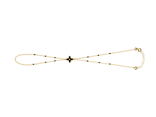 Chaîne de main en or jaune 18 carats avec motif fleur et résine noire portée sur main femme