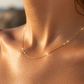 Gros plan sur le cou d'une femme portant une chaînette fine en maille fantaisie en or jaune 18 carats, un collier scintillant au style minimaliste.