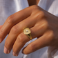 Gros plan sur une main de femme portant une chevalière en or jaune 18 carats ornée d'une étoile du Nord et d'un diamant étincelant.