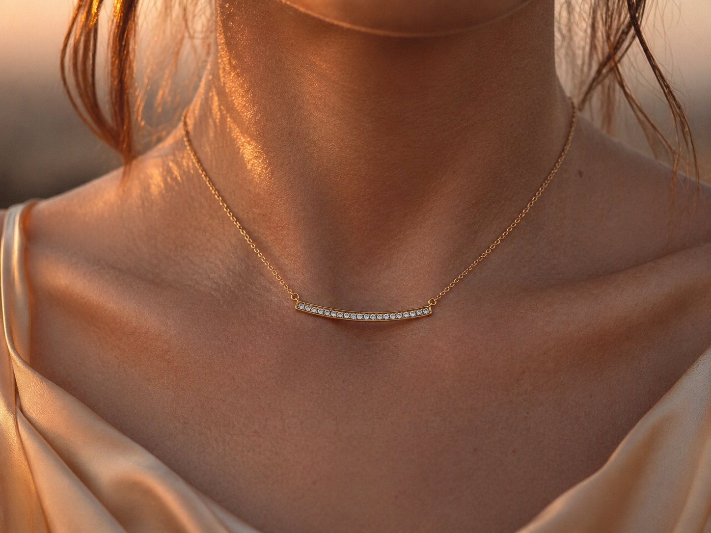 Collier barrette diamant en or jaune 18 carats porté au cou, éclat des diamants naturels sous la lumière du soleil couchant.