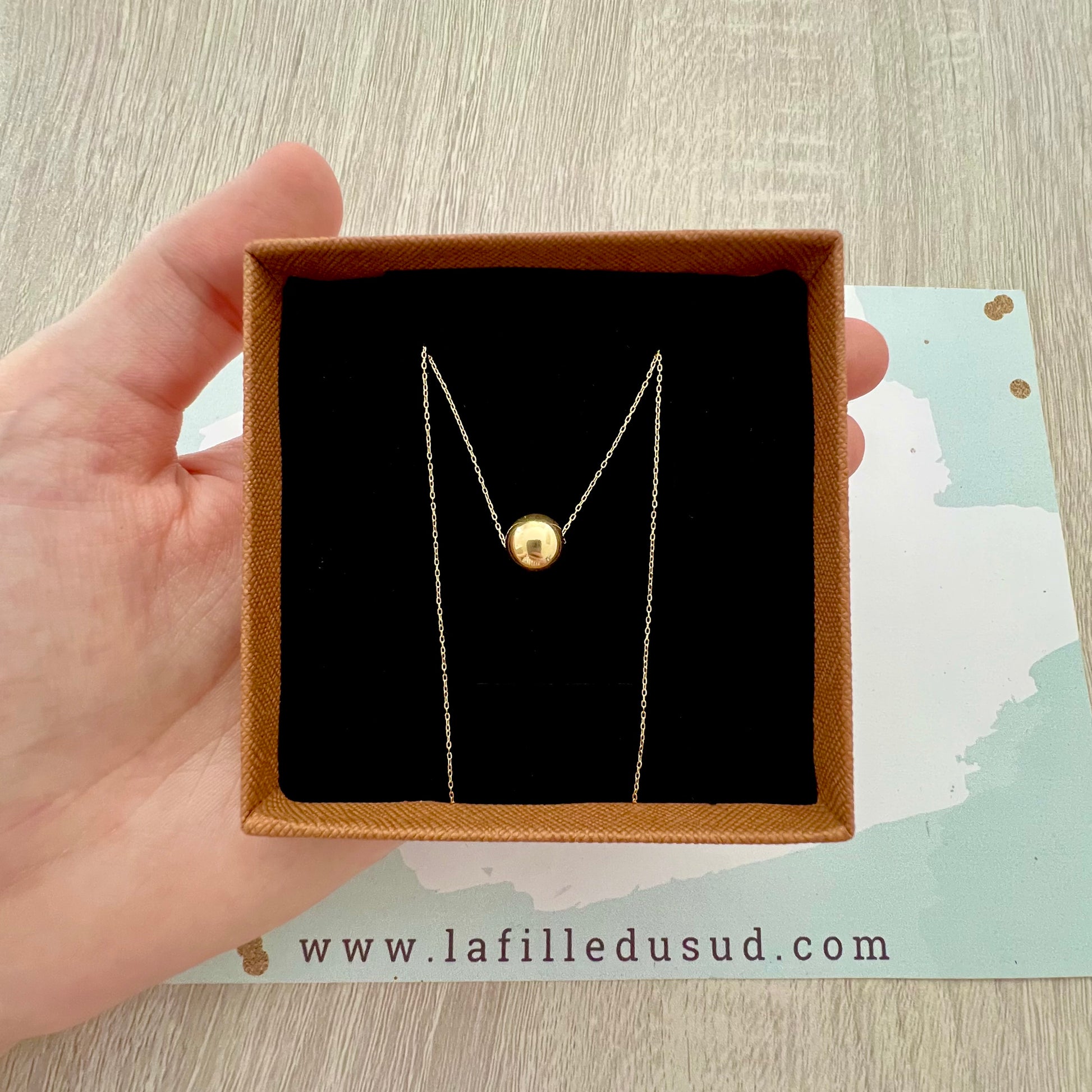 Collier pendentif boule solitaire en or jaune 18 carats présenté dans son écrin de luxe, une idée cadeau raffinée.