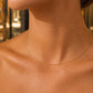 Femme portant un collier câble en or jaune 18 carats, une chaîne rigide de 1 mm au design minimaliste et élégant.