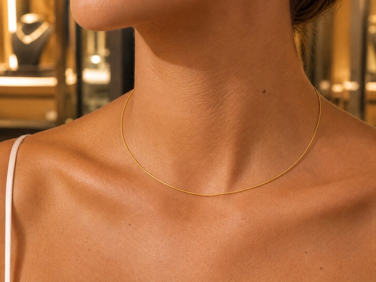 Femme portant un collier câble en or jaune 18 carats, une chaîne rigide de 1 mm au design minimaliste et élégant.