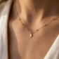 Collier catholique Vierge Marie en or jaune 18 carats porté au creux du cou d'une femme au coucher du soleil.