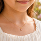 Gros plan sur le cou d'une petite fille portant un collier avec pendentif coccinelle rose en or jaune 18 carats.