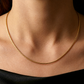 Décolleté d'une femme portant le collier maille Oméga en or jaune 18 carats de 45 cm, mettant en valeur l'éclat miroir de la chaîne de 1,4 mm.