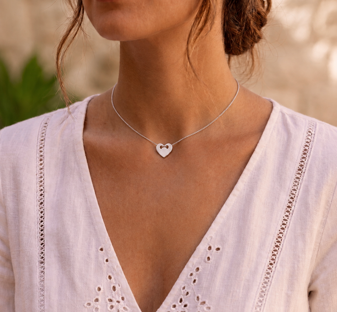 Femme portant un collier avec pendentif cœur en or blanc 18 carats massif, un bijou romantique et élégant de l'atelier La Fille du Sud.