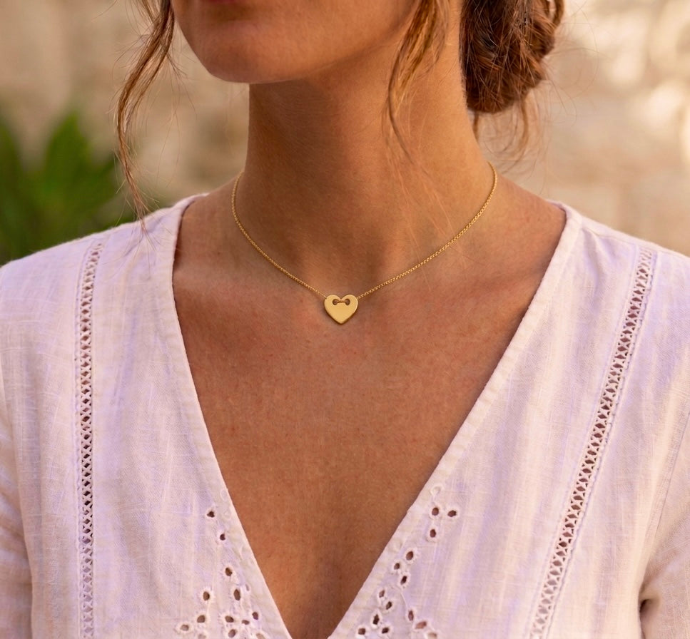 Gros plan sur une femme portant un collier avec pendentif cœur en or jaune 18 carats massif, un bijou romantique et élégant de l'atelier La Fille du Sud.
