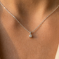 Gros plan sur le décolleté d'une femme portant un collier solitaire en or blanc 18 carats serti d'un diamant naturel de 0,15 carat.