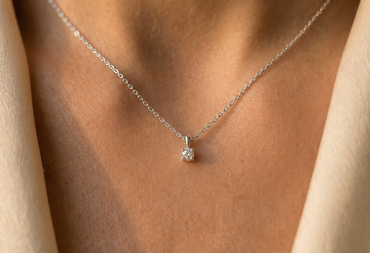 Gros plan sur le décolleté d'une femme portant un collier solitaire en or blanc 18 carats serti d'un diamant naturel de 0,15 carat.