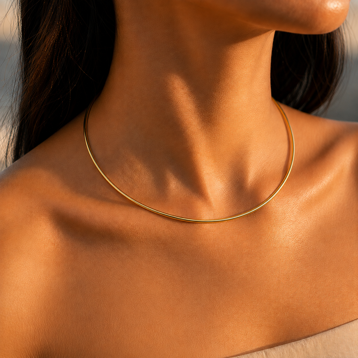 Collier jonc rigide en or jaune 18 carats porté fermé sans ouverture apparente à l'avant sous une lumière solaire.