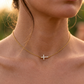 Collier ras-de-cou en or jaune 18 carats avec une croix horizontale sertie de diamants naturels, porté par une femme.