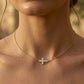 Gros plan sur le décolleté d'une femme portant un collier ras-de-cou en or jaune 18 carats avec une croix horizontale sertie de diamants naturels.